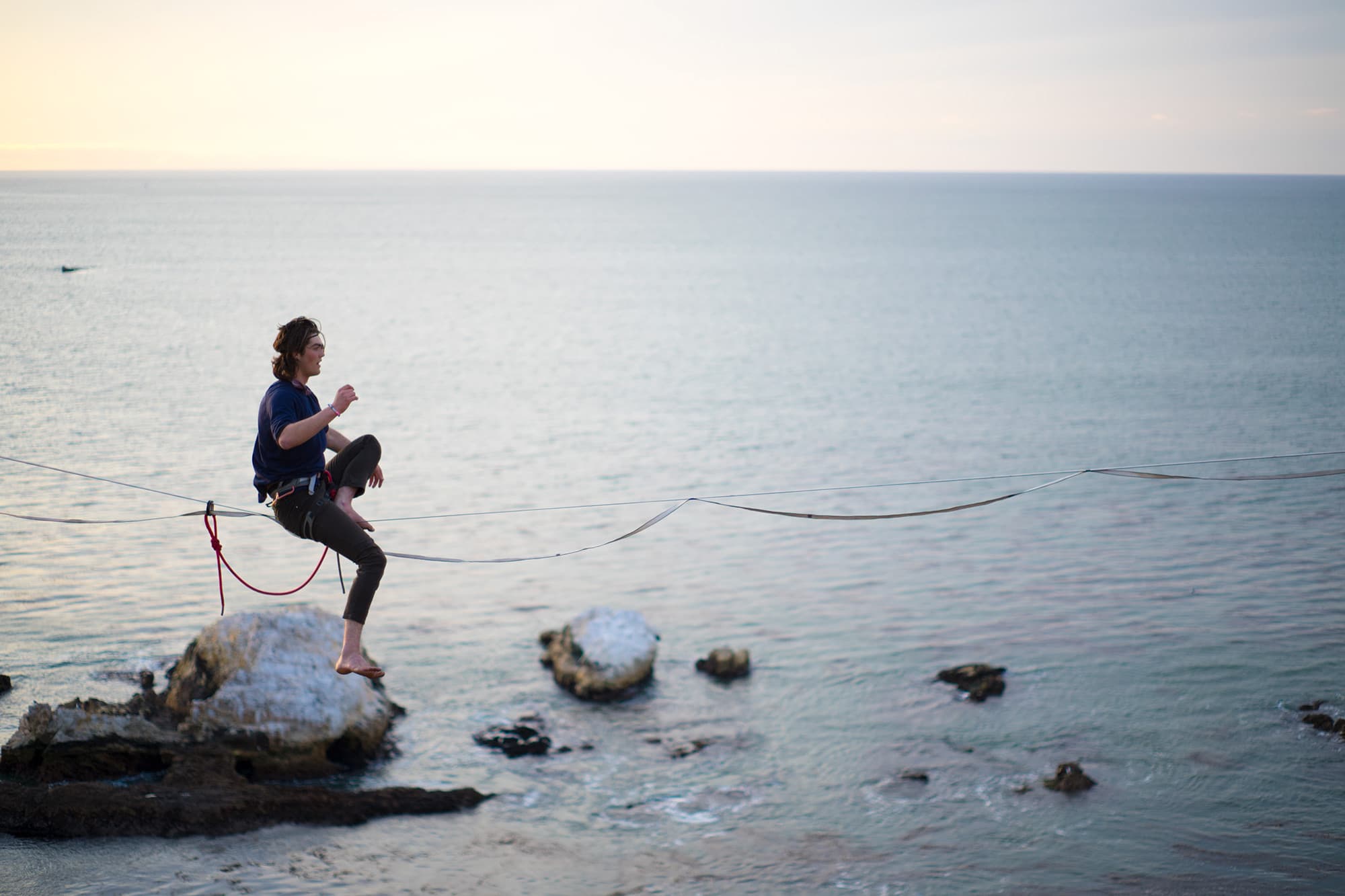 young man balancing on slack line in california over the ocean on the central coast wearing a sustainable hemp bract apparel atheltic tee