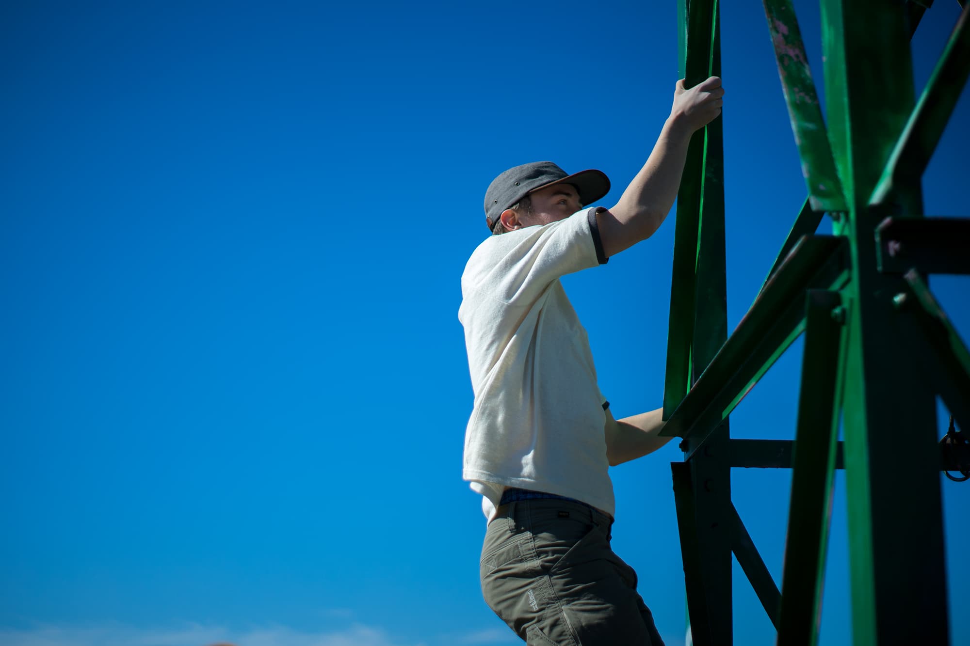 young man climbing metal tower above san luis obispo wearing sustainable hemp athletic apparel